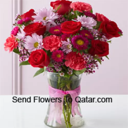Roses rouges, œillets rouges et autres fleurs assorties disposées magnifiquement dans un vase en verre