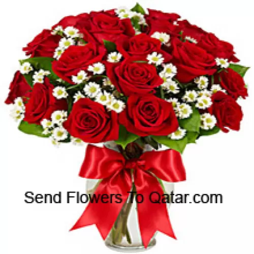 24 roses rouges avec quelques fougères dans un vase en verre