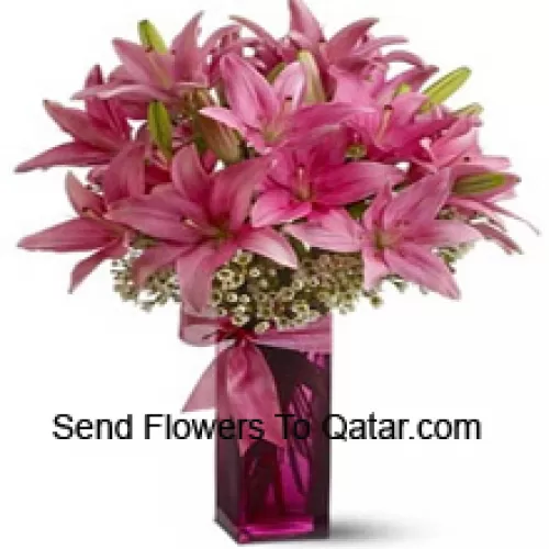 Beaux lys roses avec quelques fougères dans un vase en verre
