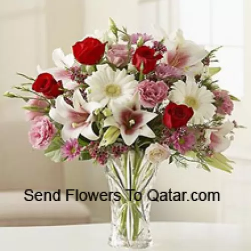 Rote Rosen, rosa Nelken, weiße Gerberas und weiße Lilien mit anderen verschiedenen Blumen in einer Glasvase