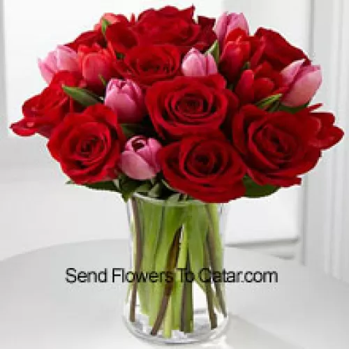 12 roses rouges et 6 tulipes roses avec quelques remplissages saisonniers dans un vase en verre