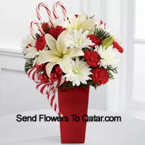 Bursts with the bright cheer and jubilant beauty of this special season. White Asiatic Lilies and chrysanthemums sit amongst red mini carnations, assorted holiday greens, red glass balls, three candy canes and festive ribbon, perfectly arranged in a red ceramic vase to create a lively bouquet of merry wishes for a splendid holiday season! (Please Note That We Reserve The Right To Substitute Any Product With A Suitable Product Of Equal Value In Case Of Non-Availability Of A Certain Product)